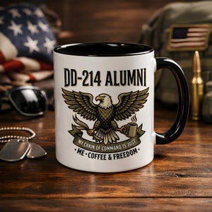 Könnte beinhalten: Weißer Keramikbecher mit schwarzem Innenraum und Griff. Der Becher zeigt den Text "DD-214 ALUMNI" über einer Adlergrafik. Darunter steht der Text "MY CHAIN OF COMMAND IS JUST ME • COFFEE & FREEDOM."