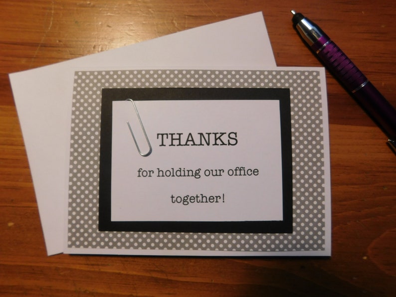 May include: A gray and white polka dot card with a black border and a black and white paperclip. The card says "THANKS for holding our office together!"