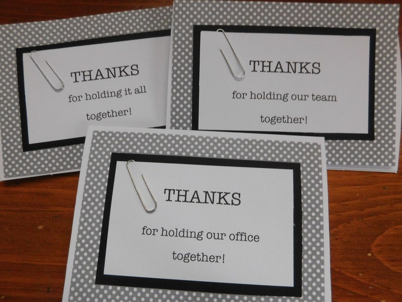 May include: Three white cards with black borders and silver paper clips. Each card has the text "THANKS" and a different message about holding something together. The cards have a gray background with white polka dots.