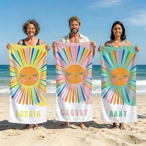 May include: Three beach towels with a smiling sun design. Each towel has a different color scheme: yellow, pink, and teal. The sun has closed eyes and a smiling mouth. Each towel has a name printed at the bottom: Sophia, Cherry, and Amy.