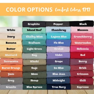 May include: A display of folded fabric samples in various colors, including white, black, blue, green, and red. The text "COLOR OPTIONS Comfort Colors 1717" is at the top, with color names like "Graphite," "Blossom," and "Espresso" labeling each fabric.