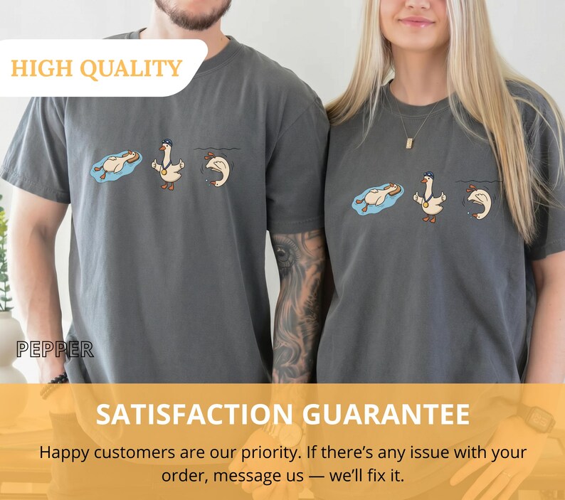 May include: Two gray t-shirts with a cartoon goose design. The design shows a goose in a pool, a goose with a medal, and a goose diving. The text "HIGH QUALITY" is at the top. The text "SATISFACTION GUARANTEE" is at the bottom.
