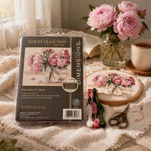 Puede incluir: Un kit de punto de cruz titulado "Peonies in Vase" con una cubierta de plástico transparente. El kit incluye hilo, aguja e instrucciones. La imagen muestra un punto de cruz terminado de peonías rosas en un jarrón, 17,7 cm x 12,7 cm.