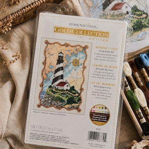 Puede incluir: Un kit de punto de cruz Dimensions Gold Collection Petites, "Luz del Marinero", con una escena de faro. El kit incluye hilo preseleccionado, un dije, Aida marfil de 18, aguja e instrucciones. Tamaño final: 12,7 cm x 17,7 cm.