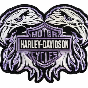 May include: A black, white, and purple embroidered patch featuring two eagle heads facing outward. Centered between the eagles is a shield-shaped emblem with the text MOTOR HARLEY-DAVIDSON CYCLES in white lettering on a purple and black background.