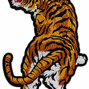May include: An embroidered patch featuring a tiger in a dynamic pose with its head turned back. The tiger has orange fur with black stripes and white accents on its underbelly and paws. The design is outlined in a thick black border.