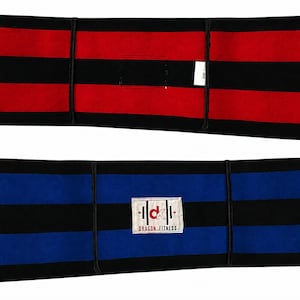 May include: Two rectangular fitness wraps featuring horizontal stripes. The top wrap is red and black with a small white tag. The bottom wrap is blue and black with a white rectangular patch displaying the text "dk" and "DRAGON FITNESS".