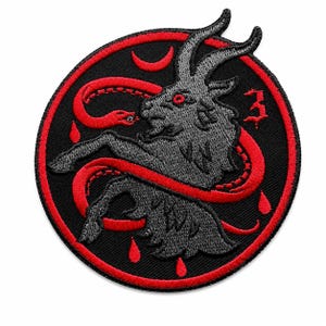 May include: A circular embroidered patch featuring a grey goat head with red eyes, surrounded by a red snake, red crescent moon, and red droplets on a black background. The number 3 is stitched in red on the right side of the circular design.