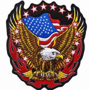 May include: An embroidered patch featuring a brown bald eagle with a white head and yellow beak, centered in front of a waving American flag. The design is surrounded by red flames and multiple white stars on a black background with a black border.