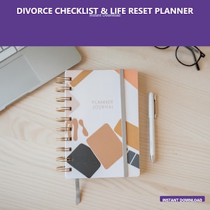 Op de afbeelding: Een spiraalgebonden planner journal met een witte omslag met abstracte geometrische vormen in bruin, oranje en grijs. De woorden "PLANNER JOURNAL" staan op de omslag. Een witte pen en een grijze elastische band zijn ook zichtbaar.