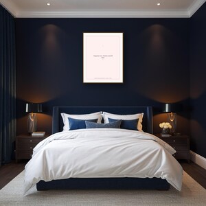 May include: A bedroom with a navy blue bed, white bedding, and decorative pillows. A framed print with the text "Organize now, thank yourself later" hangs above the bed. Two bedside tables with lamps flank the bed.