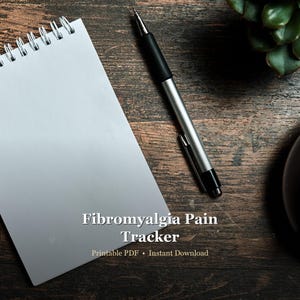 May include: A spiral-bound notepad with blank white pages, a silver and black pen, and text that reads "Fibromyalgia Pain Tracker." The text also includes "Printable PDF • Instant Download" on a dark wood grain surface.