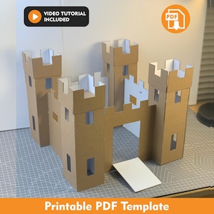 May include: A cardboard castle model featuring four tall towers with crenelated tops and a central gate with a white drawbridge. The structure includes cut-out windows and is labeled with text reading VIDEO TUTORIAL INCLUDED and Printable PDF Template.
