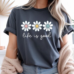 Op de afbeelding: Een set van drie keramische mokken met een gespikkelde, matte afwerking. De mokken zijn in cr&egrave;me, lichtgrijs en donkergrijs. Elke mok heeft een eenvoudig, minimalistisch ontwerp en een afgeronde handgreep.