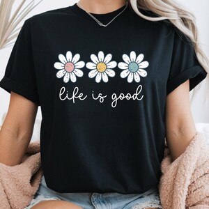 Op de afbeelding: Een witte keramische mok met een zwart handvat en de tekst "But First, Coffee" in een zwarte, handgeschreven lettertype. De mok staat op een wit oppervlak.