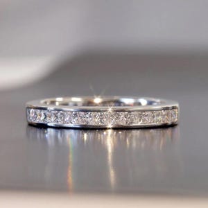 Anillo de eternidad con moissanita de talla princesa de 2 mm y circonita cúbica, engastado en canal de plata de ley.