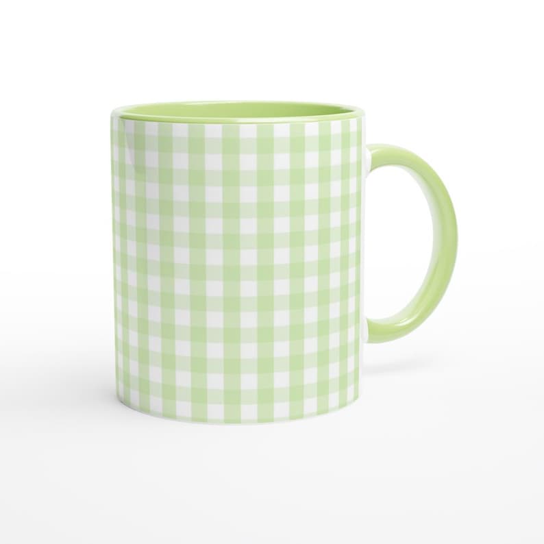 May include: A ceramic mug with a light green gingham pattern. The interior and handle are also light green. The mug is a classic coffee cup shape, perfect for hot beverages. The mug is set against a white background.