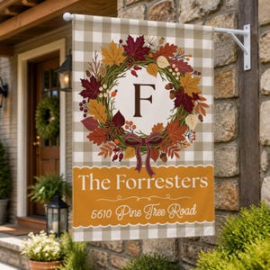 May include: A rectangular garden flag with a beige and white buffalo check pattern. It features a central autumn wreath of colorful leaves, berries, and pinecones surrounding the letter F. Below, the text reads The Forresters and 5610 Pine Tree Road.