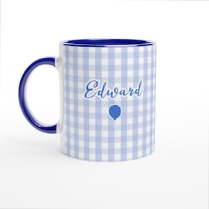May include: A white ceramic mug with a blue interior and handle. The mug features a light blue and white gingham pattern. The name "Edward" is written in cursive, with a blue balloon graphic below.