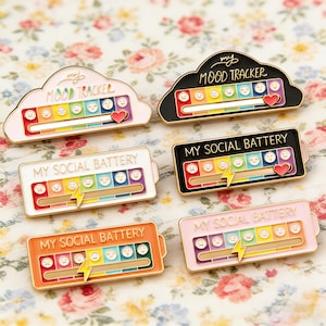 May include: A white ceramic mug with a black handle and the text "But First, Coffee" in a bold, black font. The mug is set against a blurred background, suggesting a cozy setting.