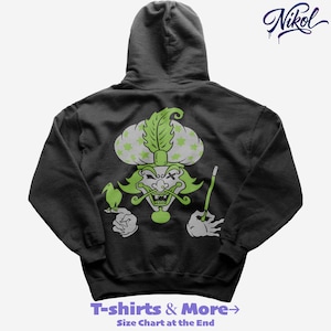 Puede incluir: Sudadera con capucha gris oscuro con una ilustración de dibujos animados en verde y blanco de un personaje con turbante, sosteniendo un pájaro y una varita. El texto "T-shirts & More" y "Size Chart at the End" están en la parte inferior.