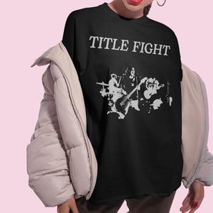 Lifestyle photo of a model wearing an oversized white t-shirt with Title Fight printed on the front.