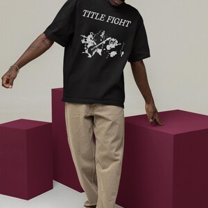 Outdoor lifestyle shot of a white unisex t-shirt, front print featuring Title Fight on the chest area.