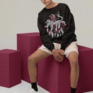 Model wearing a white long-sleeve shirt in a relaxed seated pose, displaying title fight on the front.
