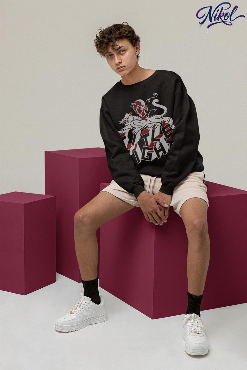 Model wearing a white long-sleeve shirt in a relaxed seated pose, displaying title fight on the front.