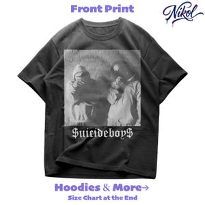 May include: A dark grey t-shirt featuring a black and white image of two people in hoodies. The text "$uicideboy$" is below the image. The shirt also has the text "Hoodies & More" and "Size Chart at the End". The brand name "Nikol" is in the upper right corner.