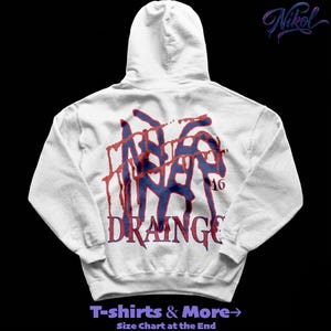 Puede incluir: Una sudadera con capucha blanca con un diseño gráfico en la espalda. El diseño presenta texto azul y rojo que dice "INA", "16" y "DRAINAGE". La sudadera también tiene el texto "T-shirts & More" en la parte inferior.