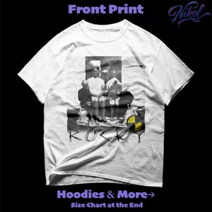 Puede incluir: Camiseta blanca con un estampado gráfico en blanco y negro de un grupo de personas. La palabra "ROCKY" está impresa en una fuente desgastada debajo del gráfico. La camiseta también tiene el texto "Hoodies & More" y "Size Chart at the End".