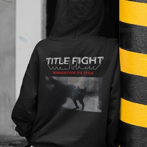 E-commerce lifestyle mockup of a white t-shirt on a model, front print shown as Title Fight.