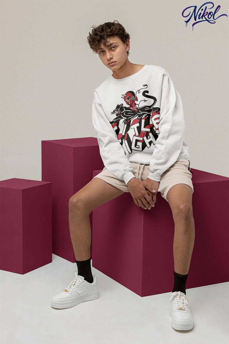 White long-sleeve t-shirt worn by a model in a seated pose, front print showing Title Fight.