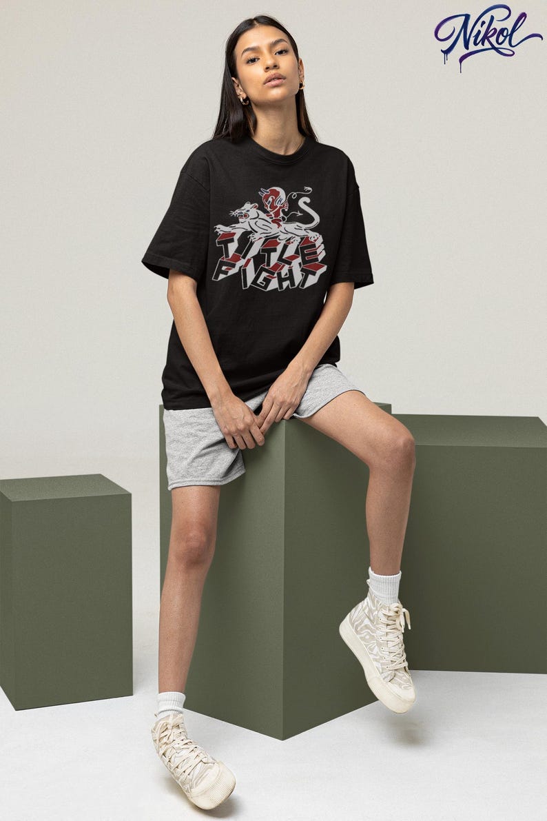 Studio lifestyle shot of a white long-sleeve tee on a model, featuring title fight on the chest area.