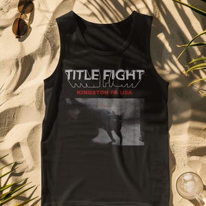 Full-body studio shot of a model in a white tee, front print featuring Title Fight on the chest area.