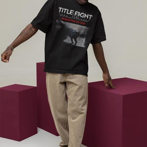 Outdoor lifestyle shot of a white unisex t-shirt, front print featuring Title Fight on the chest area.