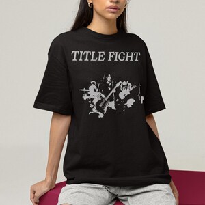 E-commerce lifestyle mockup of a white sweatshirt on a model, front print shown as Title Fight.