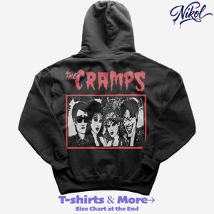 Może przedstawiać: Czarna bluza z kapturem z czerwono-białą grafiką zespołu The Cramps. Nazwa zespołu jest czerwona z tyłu, nad prostokątnym zdjęciem członków zespołu. Tekst "T-shirts & More" znajduje się na dole bluzy.