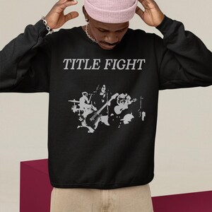 Back-facing hoodie lifestyle image, white hoodie with Title Fight displayed on the back print area.