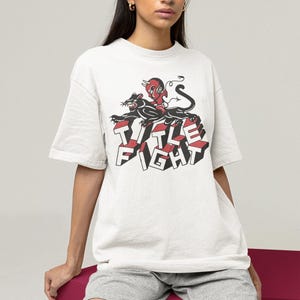 E-commerce lifestyle mockup of a white oversized tee on a model, front print shown as Title Fight.