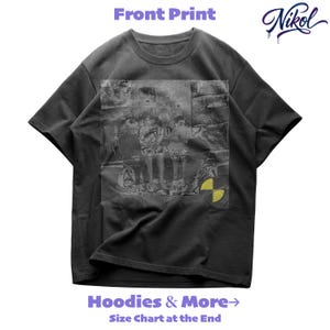 Puede incluir: Camiseta gris oscuro con estampado frontal que presenta una imagen descolorida en escala de grises de tres figuras y un símbolo de peligro amarillo. La camiseta tiene el texto "Front Print" en la parte superior y "Hoodies & More" y "Size Chart at the End" en la parte inferior.