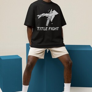 Flat lay white tank top in a beach-style scene, front print showcasing title fight on the chest area.