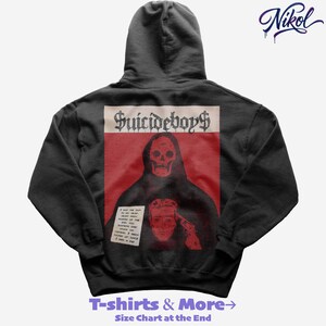 Puede incluir: Sudadera con capucha gris oscuro con un diseño gráfico que presenta una calavera y el texto "Suicideboys". El diseño está sobre un fondo rojo. La sudadera con capucha también tiene el texto "T-shirts & More" en la parte inferior.
