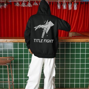 E-commerce lifestyle mockup of a white t-shirt on a model, front print displaying title fight.