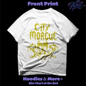 以下が含まれることがあります： 白いTシャツに金色のグラフィック。デザインには「CITY MORGUE」の文字と三つ頭の犬が含まれています。Tシャツはクルーネックと半袖です。「Hoodies & More」と「Size Chart at the End」の文字が下にあります。