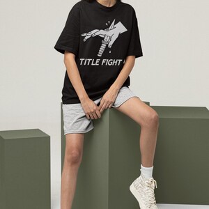 Front print lifestyle image of a white long-sleeve tee, title fight displayed with natural fabric folds.