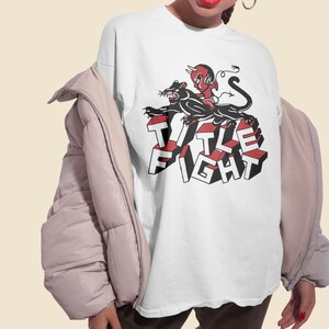 Lifestyle photo of a model wearing a white t-shirt with title fight printed on the front.