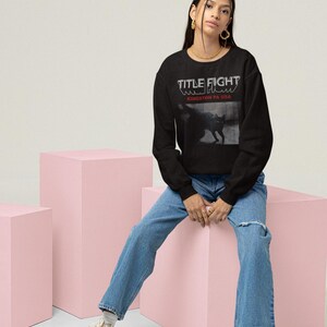 Casual studio outfit photo with a white long-sleeve shirt, showcasing Title Fight on the front.