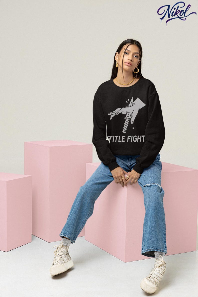 Studio lifestyle shot of a white long-sleeve t-shirt, front print preview featuring title fight.